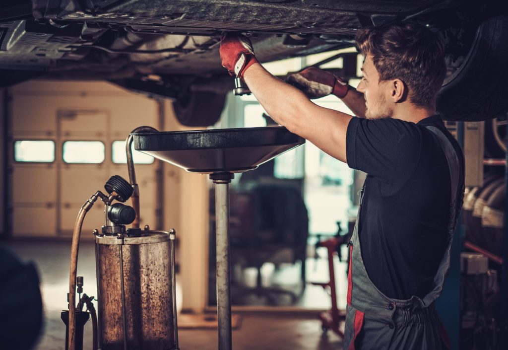 Mecánico que se pregunta cuál aceite de motor es mejor, cambiando el aceite de un moetor