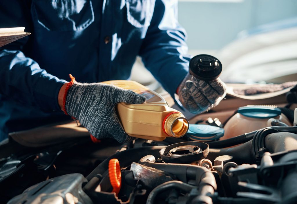 Un mecánico poniendo aceite de motor en un coche