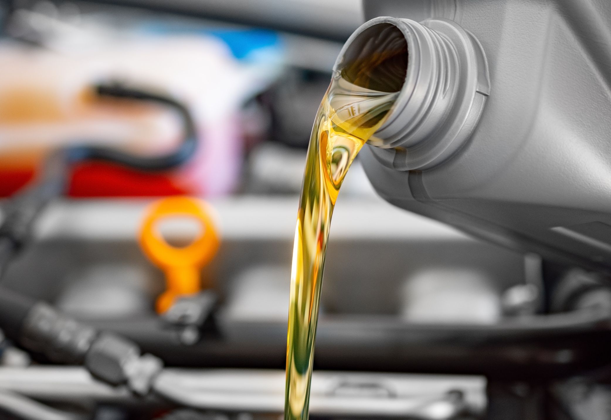 Aceite de motor amarillo vertiéndose sobre un motor de coche