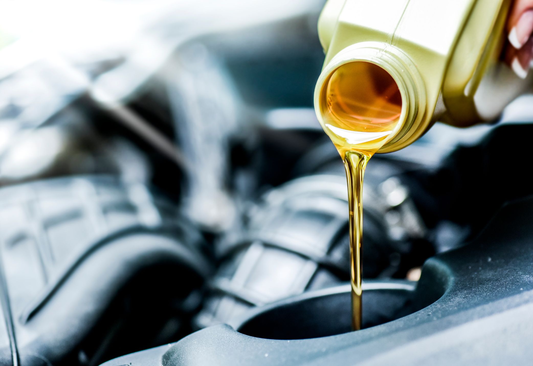 Un motor recibiendo aceite de una botella amarilla