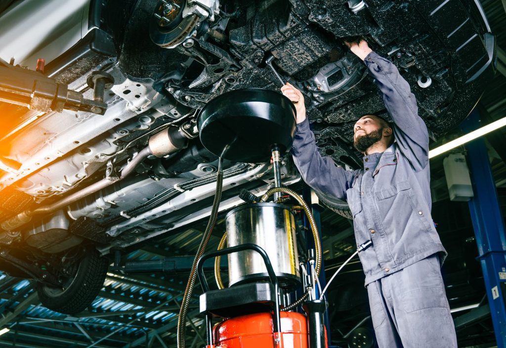 Una persona cambiando el aceite de motor de su coche. 