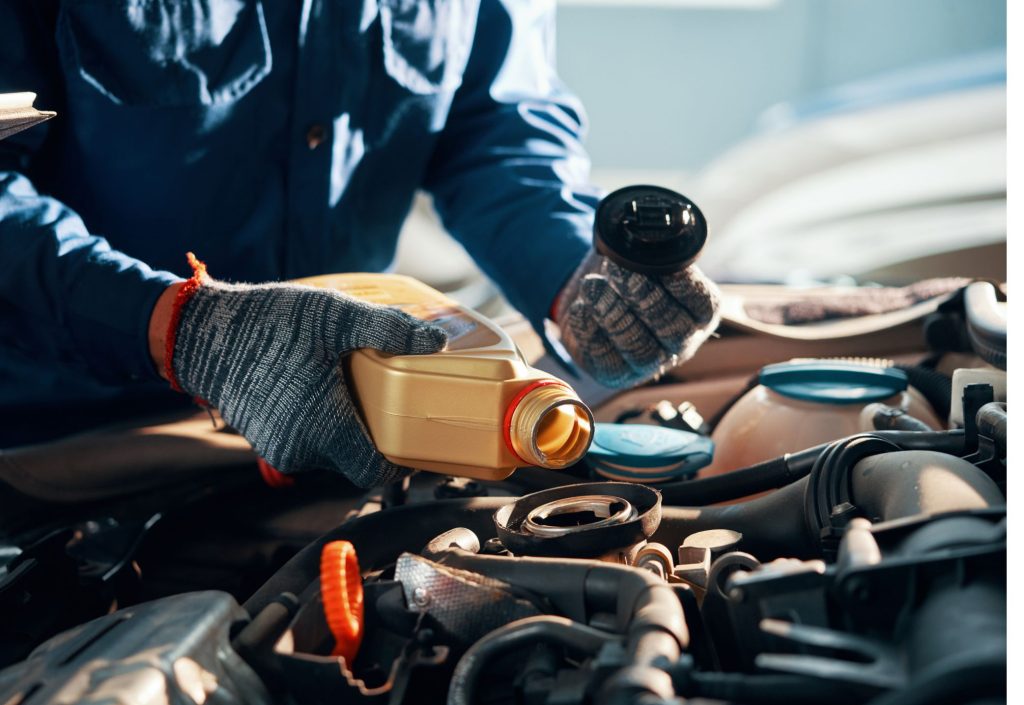 Un mecánico poniendo aceite a un motor, mientras se pregunta ¿Qué pasa si cambio de aceite mineral a sintético?
