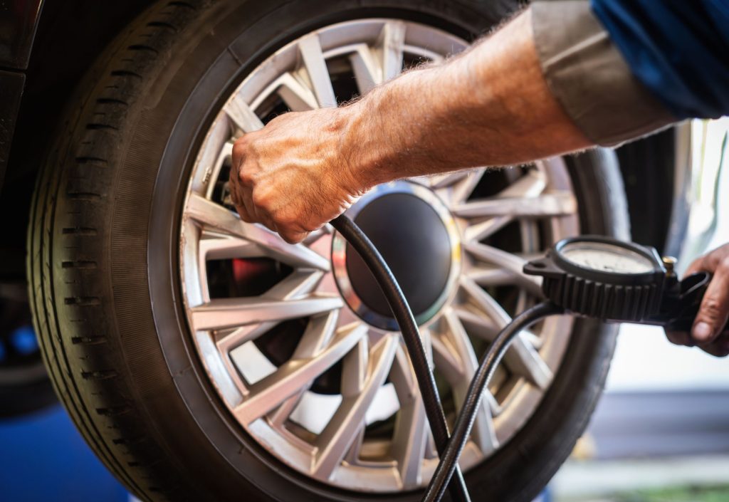 Un mecánico que se pregunta a cuánto calibrar las llantas, checando la presión de una llanta
