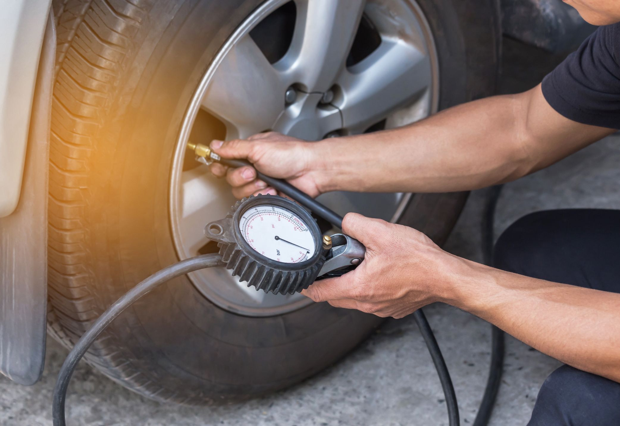 Un dueño de auto calibrando la presión de sus llantas con un dispositivo
