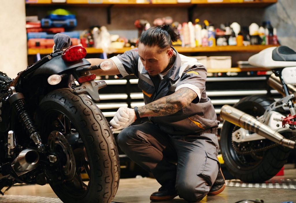 Un dueño de una moto preguntándose a cuánto se calibran las llantas de moto, mientras repara la llanta de su moto